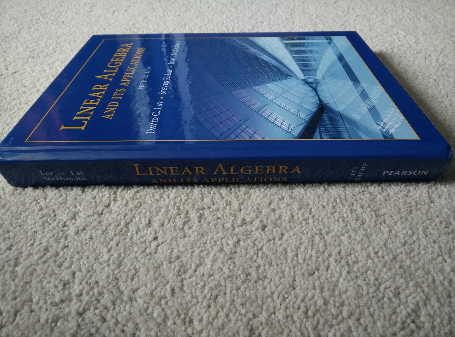 Front cover of the hardcover textbook 'Linear Algebra and Its Applications' Fifth Edition by David C. Lay, Steven R. Lay, and Judi J. McDonald, featuring a modern architectural building interior.