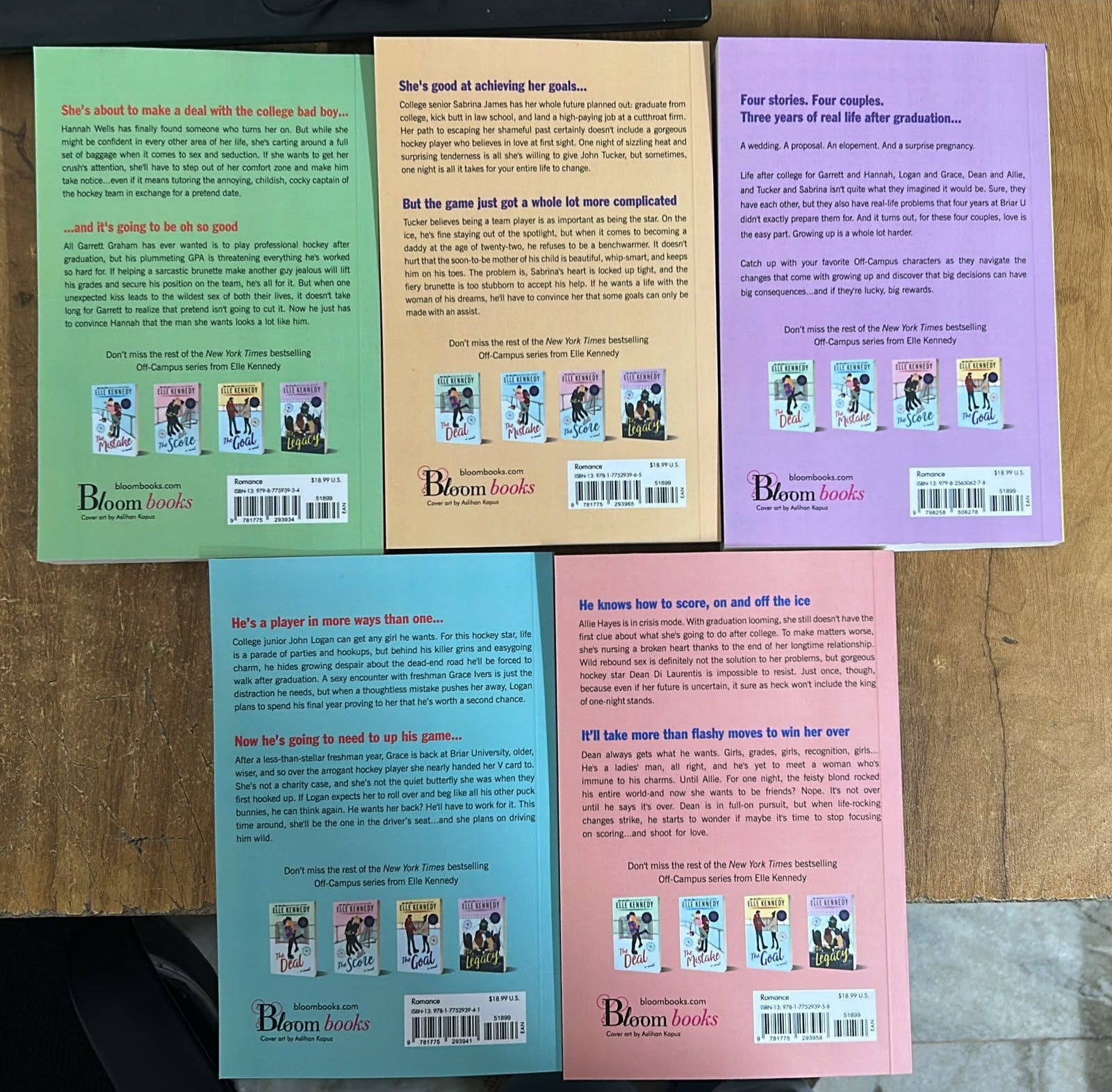 Five paperback books from the brand Dream Books, showing their colorful back covers in shades of blue, green, beige, pink, and purple, arranged on a wooden surface.